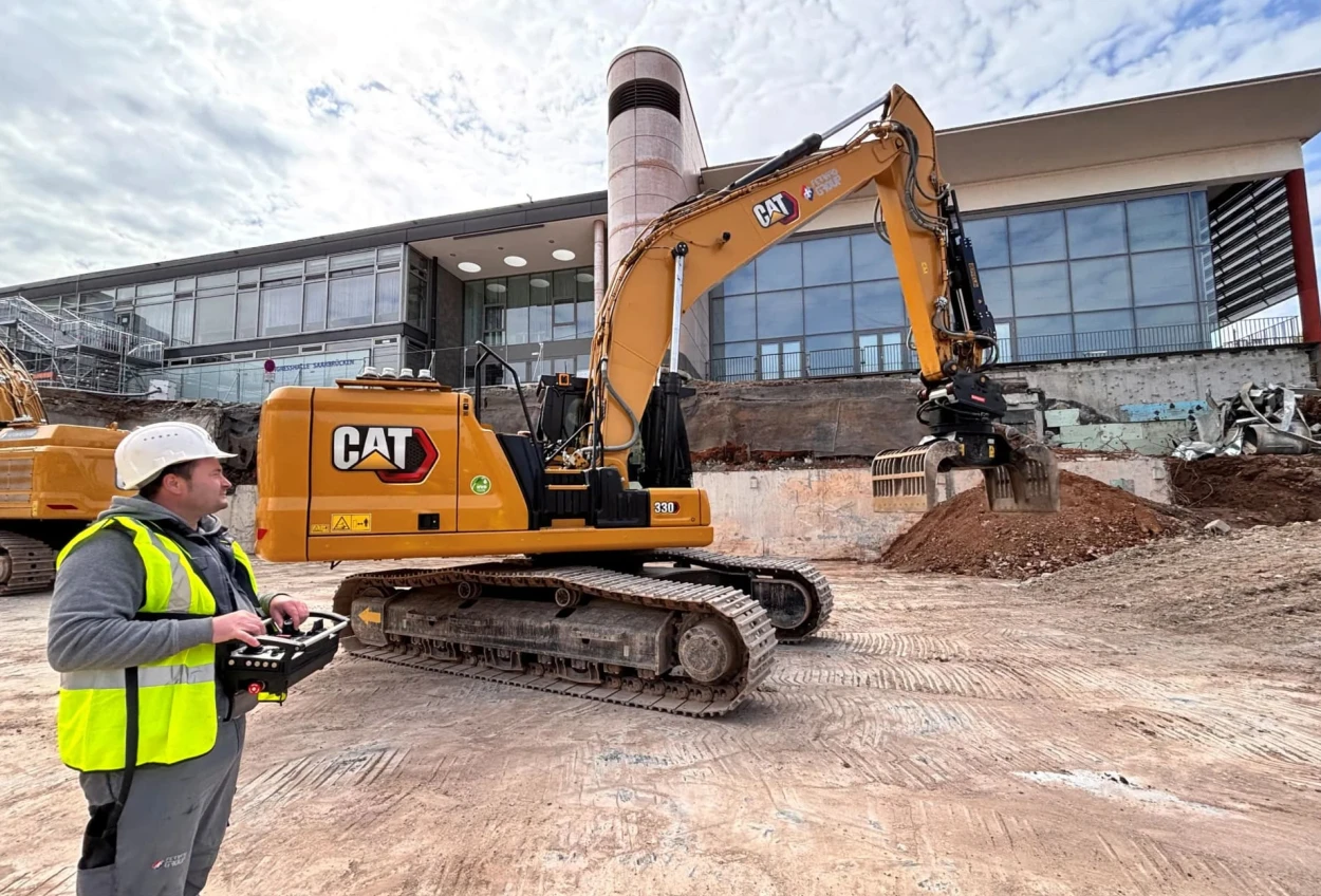 Fahrer Iulian Chirila bewegt den Cat 330 mit einer Steuerkonsole. Bild (c) Zeppelin Baumaschinen GmbH